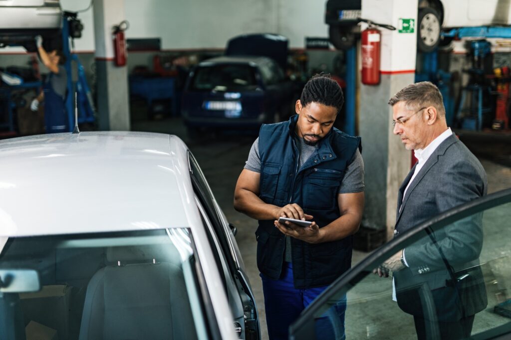 African American mechanic and businessman using digital tablet in auto repair shop.