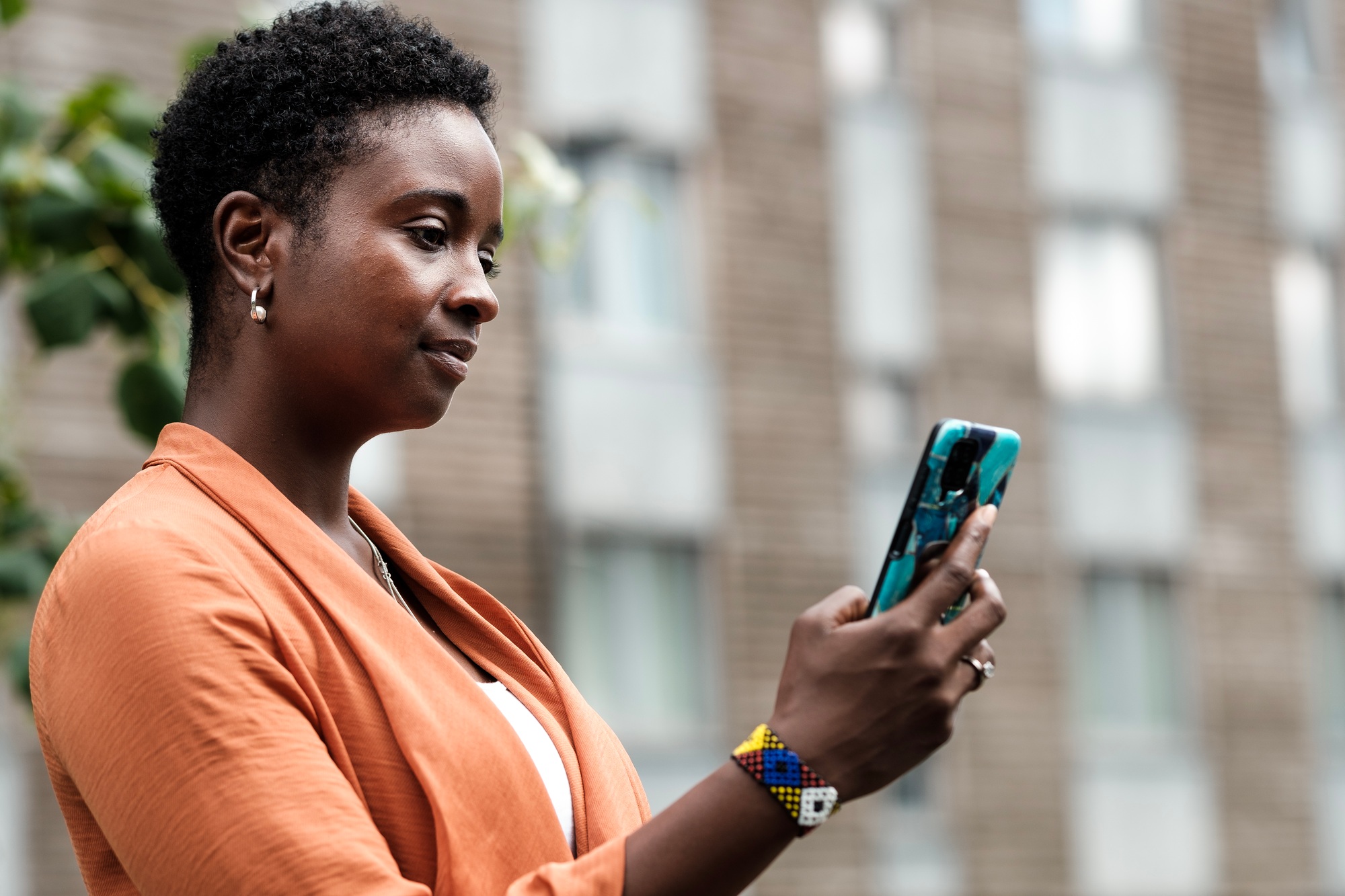 Black woman reading on her phone outside.